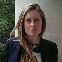 blonde female looks at camera wearing navy jacket